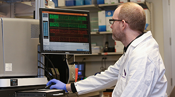 man in white lab coat reviewing data on computer